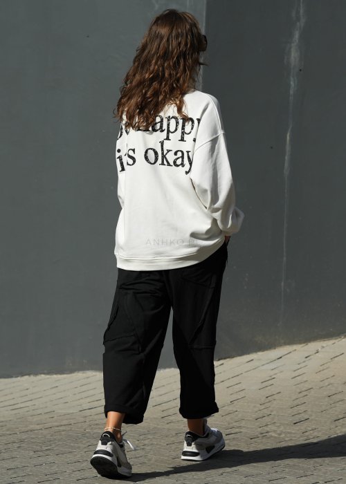 Czarne spodnie dresowe damskie o luźnym kroju baggy z ozdobnymi przeszyciami i gumką w pasie, stylizowane ze sneakersami w miejskim looku.