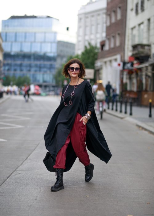 Bordowe spodnie dresowe damskie z obniżonym krokiem i ozdobnymi przeszyciami, luźny fason z gumką w pasie i sznurkiem, stylizacja miejska z czarnymi botkami.