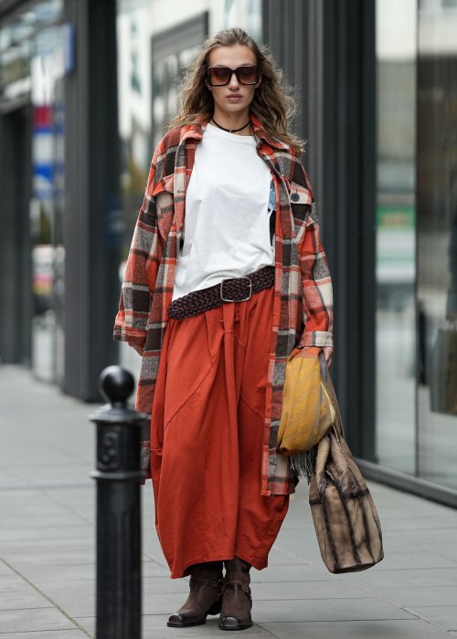 Ceglana spódnica maxi typu bombka z elastycznym pasem i przeszyciami, zestawiona z jasną bluzką i botkami w miejskiej stylizacji.