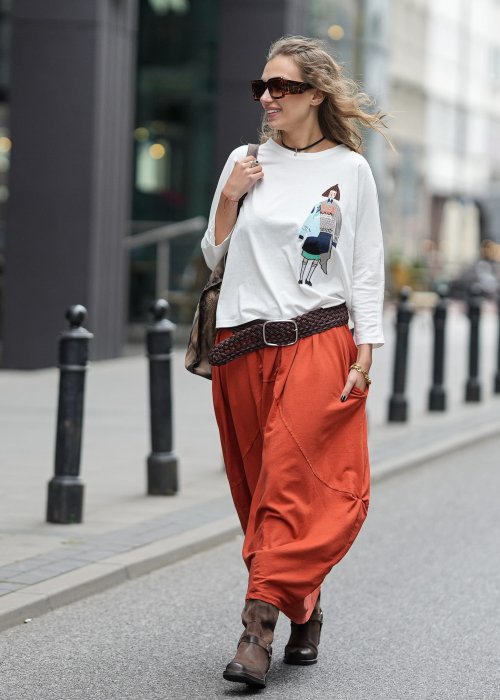 Ceglana spódnica maxi typu bombka z elastycznym pasem i przeszyciami, zestawiona z jasną bluzką i botkami w miejskiej stylizacji.