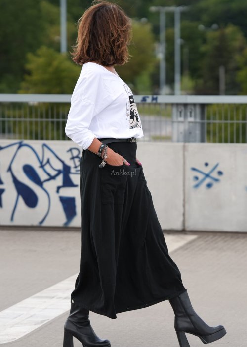Czarne spódnico-spodnie maxi z elastycznym pasem i dużymi kieszeniami, zestawione z białą bluzką i czarnymi botkami na obcasie w miejskiej stylizacji.