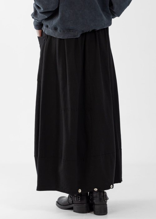 Czarne spódnico-spodnie maxi z elastycznym pasem i dużymi kieszeniami, zestawione z białą bluzką i czarnymi botkami na obcasie w miejskiej stylizacji.