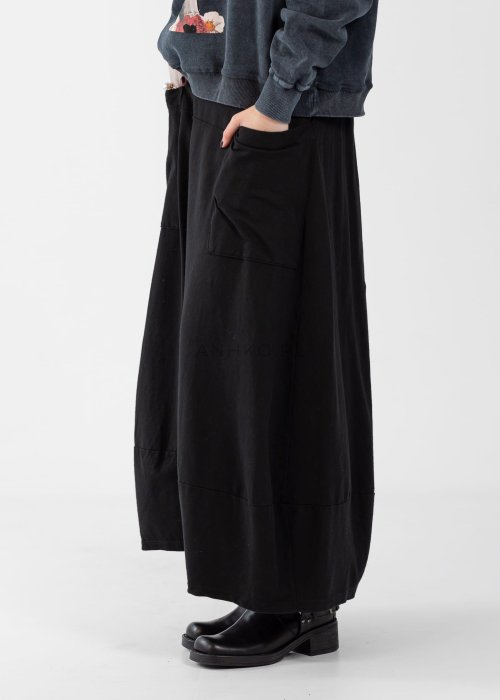 Czarne spódnico-spodnie maxi z elastycznym pasem i dużymi kieszeniami, zestawione z białą bluzką i czarnymi botkami na obcasie w miejskiej stylizacji.