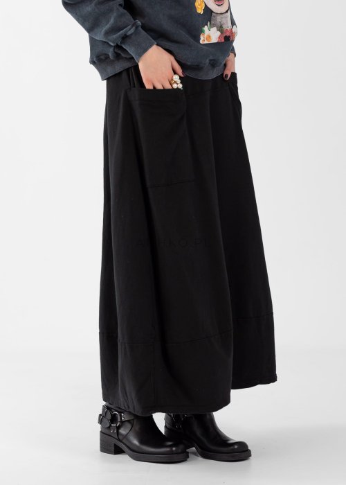 Czarne spódnico-spodnie maxi z elastycznym pasem i dużymi kieszeniami, zestawione z białą bluzką i czarnymi botkami na obcasie w miejskiej stylizacji.