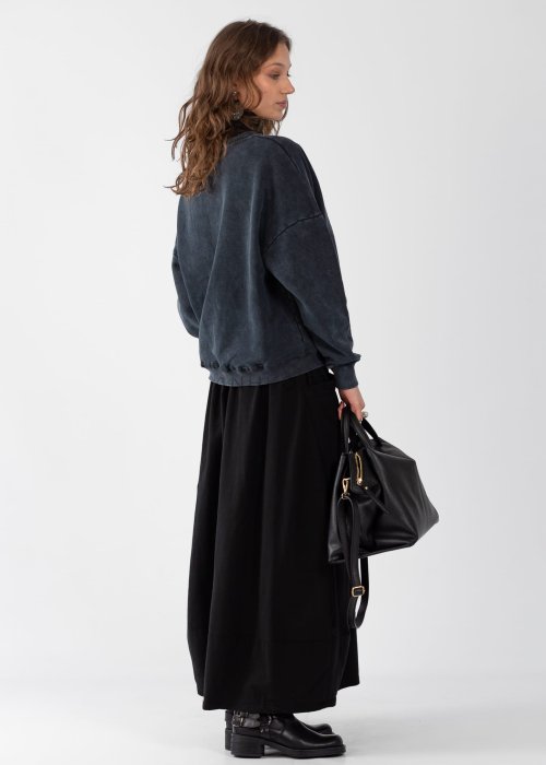 Czarne spódnico-spodnie maxi z elastycznym pasem i dużymi kieszeniami, zestawione z białą bluzką i czarnymi botkami na obcasie w miejskiej stylizacji.