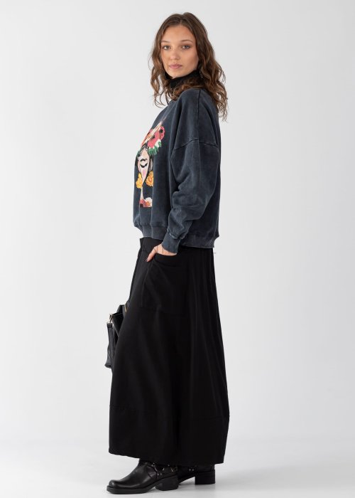 Czarne spódnico-spodnie maxi z elastycznym pasem i dużymi kieszeniami, zestawione z białą bluzką i czarnymi botkami na obcasie w miejskiej stylizacji.