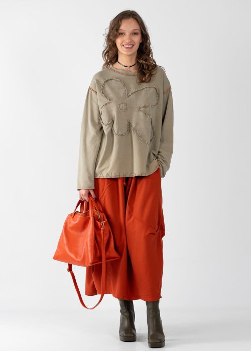 Ceglana spódnica maxi typu bombka z elastycznym pasem i przeszyciami, zestawiona z jasną bluzką i botkami w miejskiej stylizacji.