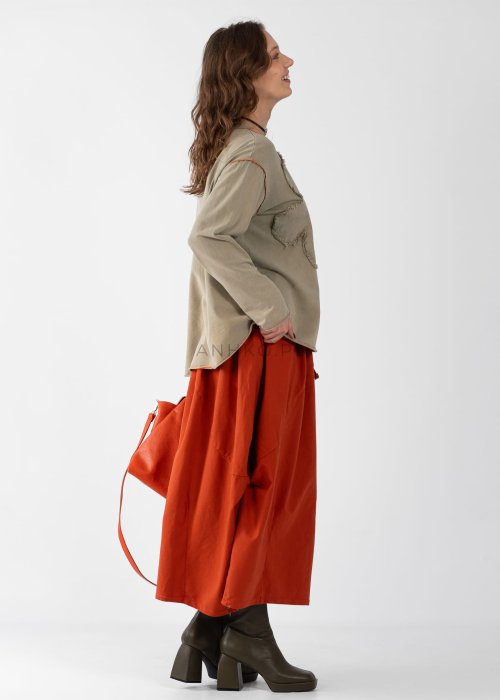 Ceglana spódnica maxi typu bombka z elastycznym pasem i przeszyciami, zestawiona z jasną bluzką i botkami w miejskiej stylizacji.