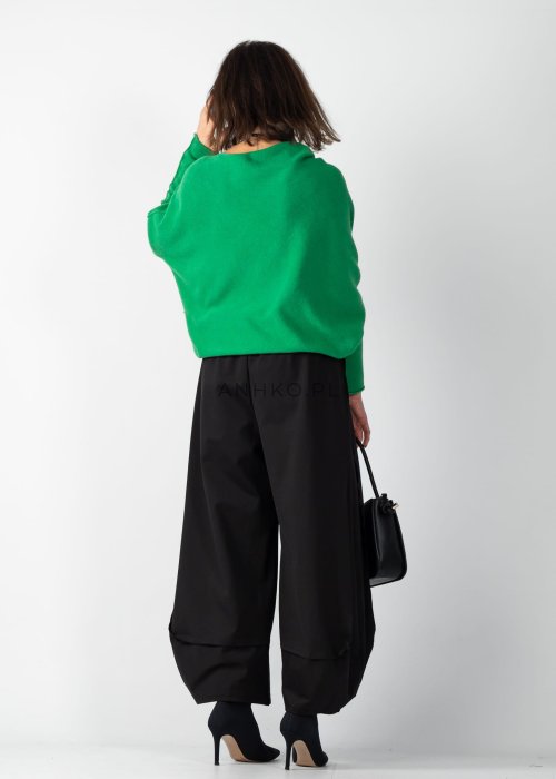 Zielony sweter damski oversize o nietoperzowym kroju z asymetrycznym dołem, stylizacja z czarną spódnicą.