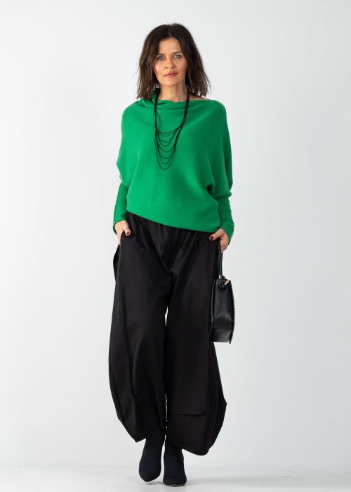Zielony sweter damski oversize o nietoperzowym kroju z asymetrycznym dołem, stylizacja z czarną spódnicą.