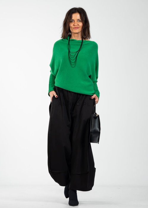 Zielony sweter damski oversize o nietoperzowym kroju z asymetrycznym dołem, stylizacja z czarną spódnicą.