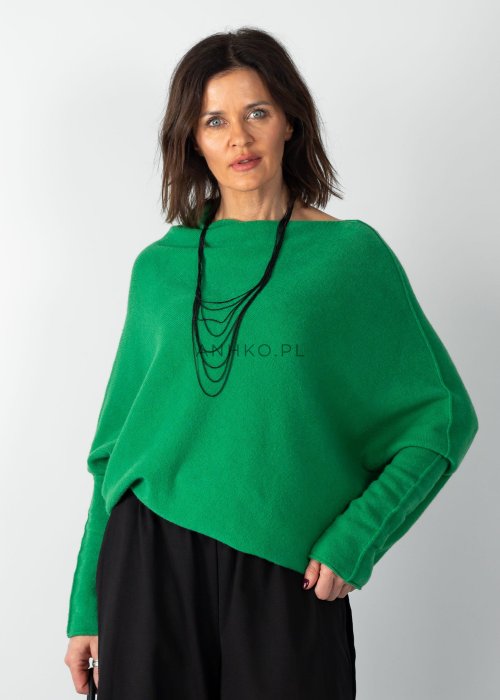 Zielony sweter damski oversize o nietoperzowym kroju z asymetrycznym dołem, stylizacja z czarną spódnicą.