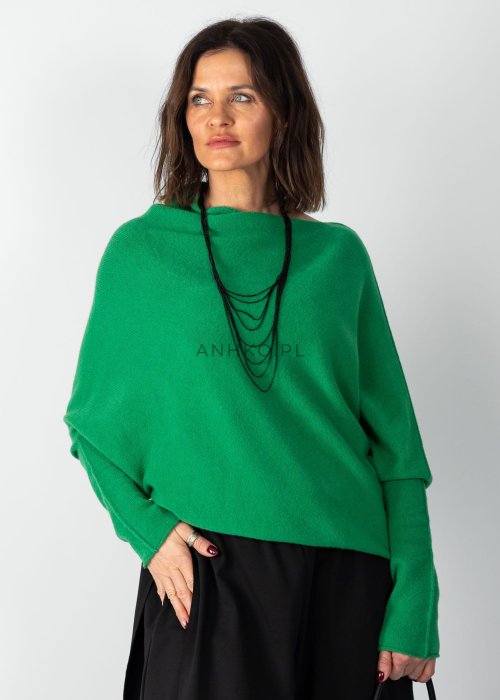 Zielony sweter damski oversize o nietoperzowym kroju z asymetrycznym dołem, stylizacja z czarną spódnicą.