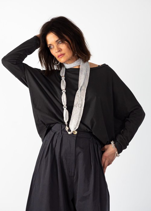 Czarna bluzka oversize z długim rękawem i szerokim dekoltem, zestawiona z jasnoniebieską spódnicą w nowoczesnej, miejskiej stylizacji.