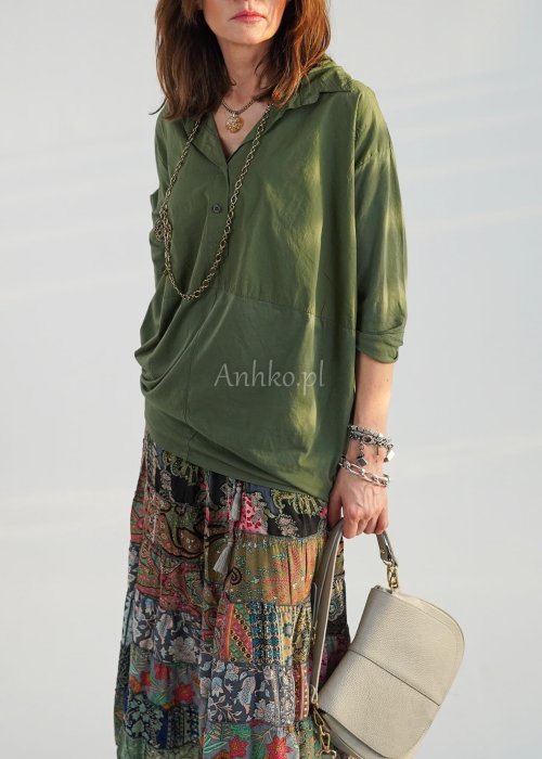 Khaki koszula damska oversize z kołnierzykiem i przeszyciem poniżej biustu, zestawiona z wzorzystą spódnicą maxi i botkami w stylizacji casual.