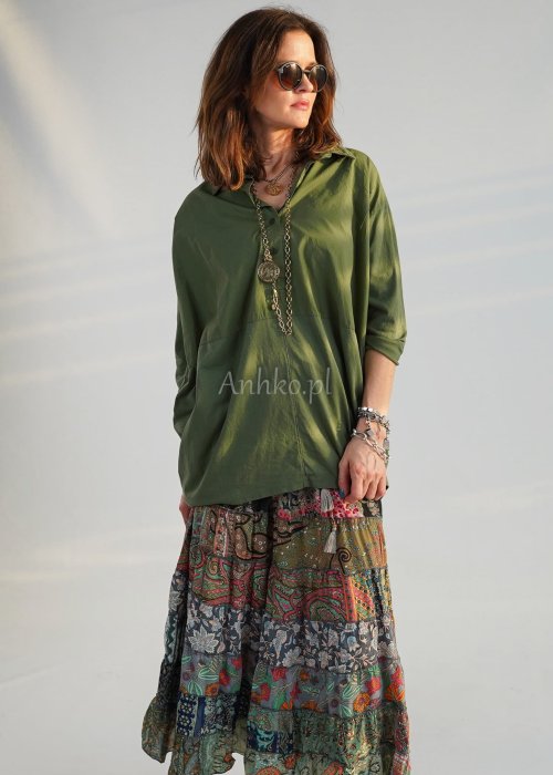 Khaki koszula damska oversize z kołnierzykiem i przeszyciem poniżej biustu, zestawiona z wzorzystą spódnicą maxi i botkami w stylizacji casual.