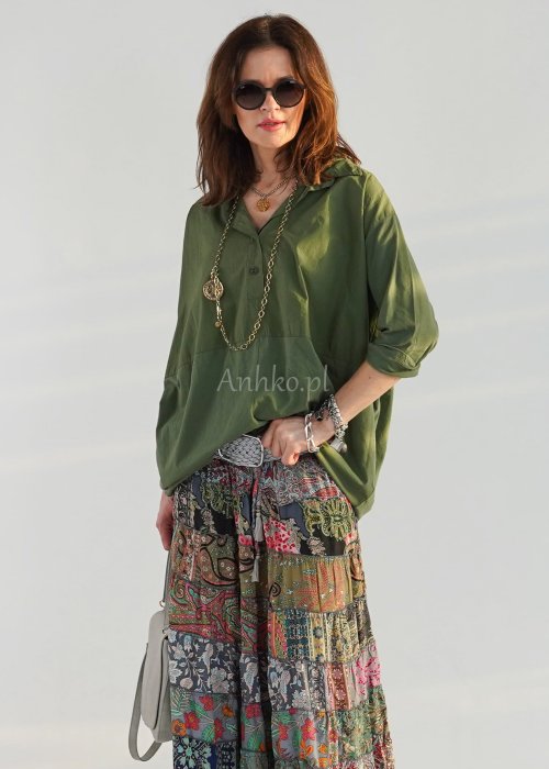 Khaki koszula damska oversize z kołnierzykiem i przeszyciem poniżej biustu, zestawiona z wzorzystą spódnicą maxi i botkami w stylizacji casual.