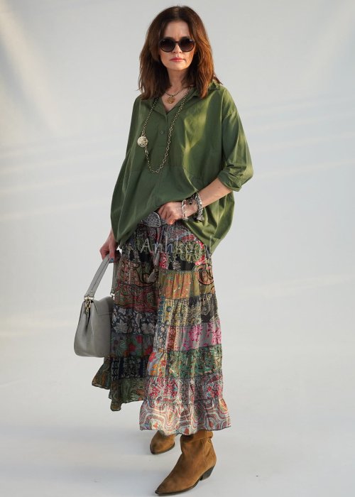 Khaki koszula damska oversize z kołnierzykiem i przeszyciem poniżej biustu, zestawiona z wzorzystą spódnicą maxi i botkami w stylizacji casual.