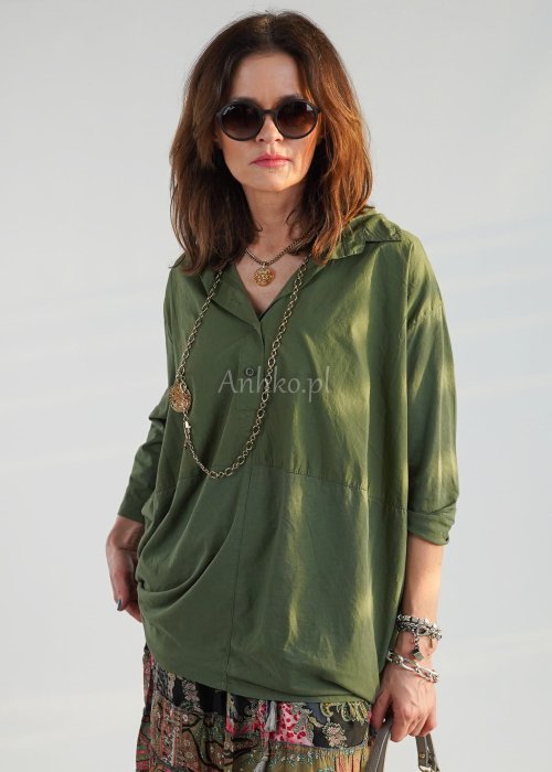 Khaki koszula damska oversize z kołnierzykiem i przeszyciem poniżej biustu, zestawiona z wzorzystą spódnicą maxi i botkami w stylizacji casual.