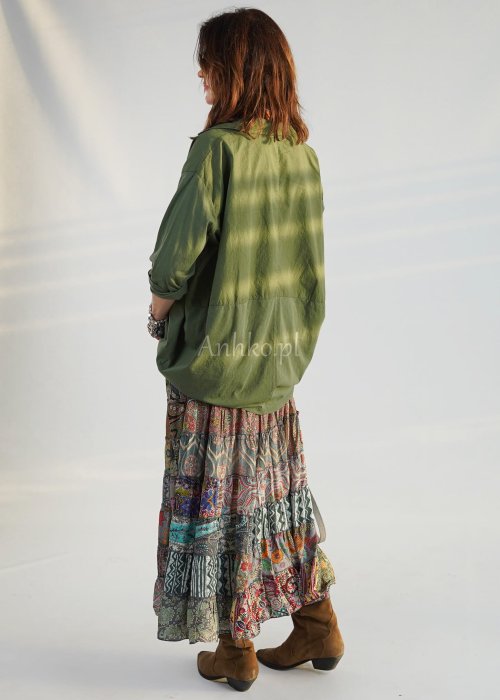 Khaki koszula damska oversize z kołnierzykiem i przeszyciem poniżej biustu, zestawiona z wzorzystą spódnicą maxi i botkami w stylizacji casual.