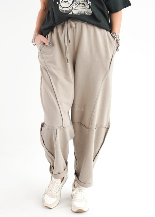 Beżowe spodnie oversize z obniżonym krokiem i dekoracyjnymi przeszyciami, luźny fason, miejska stylizacja damska.