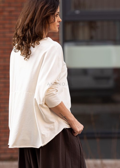 Śmietankowa bluza damska oversize z długim rękawem i naszywką na froncie. Luźny fason w stylizacji z szerokimi spodniami w miejskim stylu.