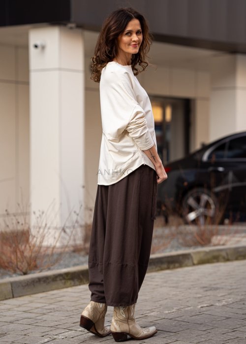 Śmietankowa bluza damska oversize z długim rękawem i naszywką na froncie. Luźny fason w stylizacji z szerokimi spodniami w miejskim stylu.