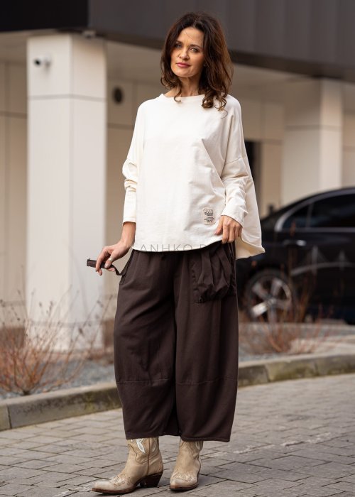 Śmietankowa bluza damska oversize z długim rękawem i naszywką na froncie. Luźny fason w stylizacji z szerokimi spodniami w miejskim stylu.