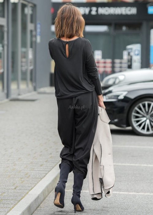 Czarne spodnie damskie z elastycznym pasem i zwężaną nogawką, zestawione z oversize bluzką i botkami w nowoczesnej stylizacji miejskiej.
