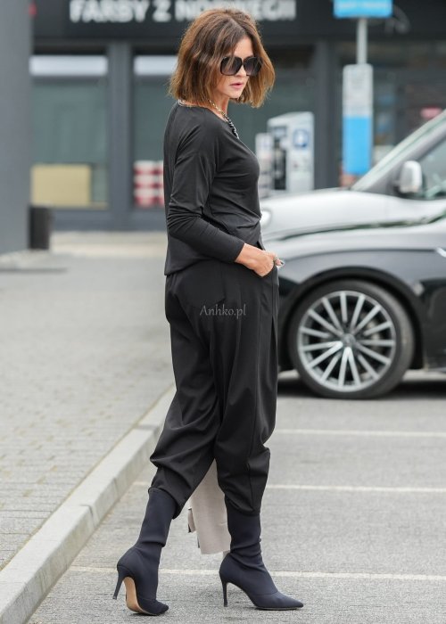 Czarne spodnie damskie z elastycznym pasem i zwężaną nogawką, zestawione z oversize bluzką i botkami w nowoczesnej stylizacji miejskiej.