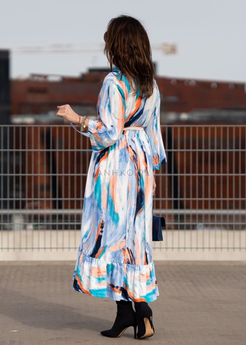 Sukienka maxi w artystyczny print w odcieniach błękitu, pomarańczu i granatu z efektownym wiązaniem w talii. Zwiewny fason z falbaną przy dole oraz koszulową górą nadaje sylwetce lekkości i elegancji.