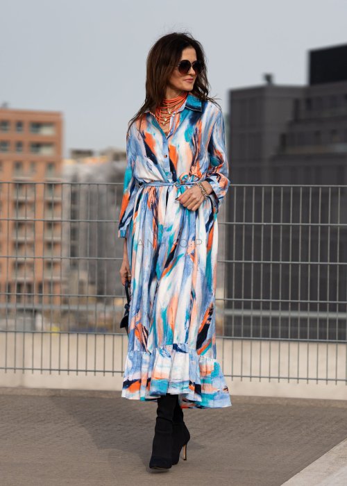 Sukienka maxi w artystyczny print w odcieniach błękitu, pomarańczu i granatu z efektownym wiązaniem w talii. Zwiewny fason z falbaną przy dole oraz koszulową górą nadaje sylwetce lekkości i elegancji.