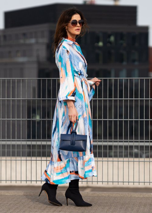 Sukienka maxi w artystyczny print w odcieniach błękitu, pomarańczu i granatu z efektownym wiązaniem w talii. Zwiewny fason z falbaną przy dole oraz koszulową górą nadaje sylwetce lekkości i elegancji.