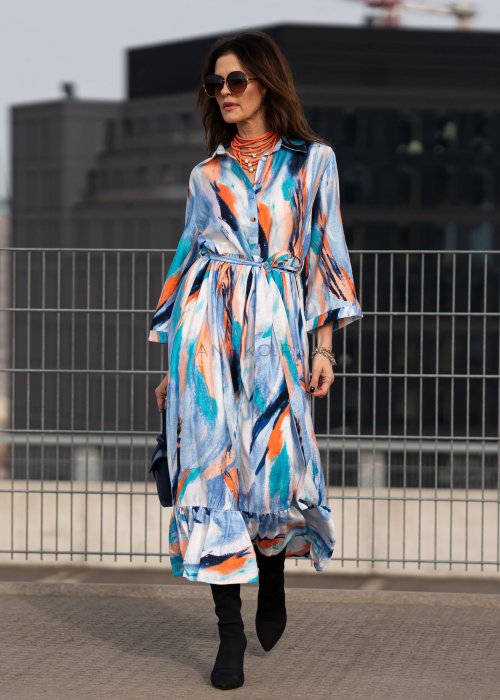 Sukienka maxi w artystyczny print w odcieniach błękitu, pomarańczu i granatu z efektownym wiązaniem w talii. Zwiewny fason z falbaną przy dole oraz koszulową górą nadaje sylwetce lekkości i elegancji.