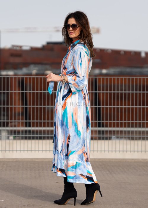Sukienka maxi w artystyczny print w odcieniach błękitu, pomarańczu i granatu z efektownym wiązaniem w talii. Zwiewny fason z falbaną przy dole oraz koszulową górą nadaje sylwetce lekkości i elegancji.