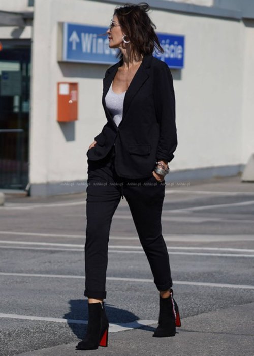 Czarna marynarka damska o klasycznym kroju, dzianinowa, noszona w miejskiej stylizacji z dopasowanymi spodniami i topem.
