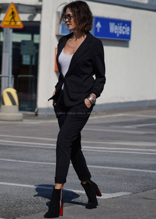 Czarna marynarka damska o klasycznym kroju, dzianinowa, noszona w miejskiej stylizacji z dopasowanymi spodniami i topem.