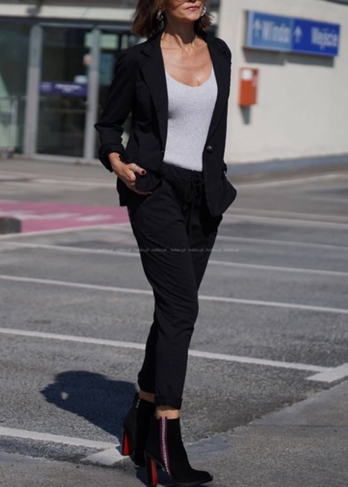 Czarna marynarka damska o klasycznym kroju, dzianinowa, noszona w miejskiej stylizacji z dopasowanymi spodniami i topem.