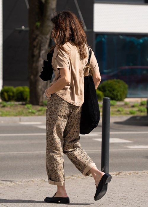 Bluzka damska w odcieniu camel z szerokim dekoltem i krótkim rękawem, zestawiona ze spodniami w zwierzęcy wzór w miejskiej stylizacji.