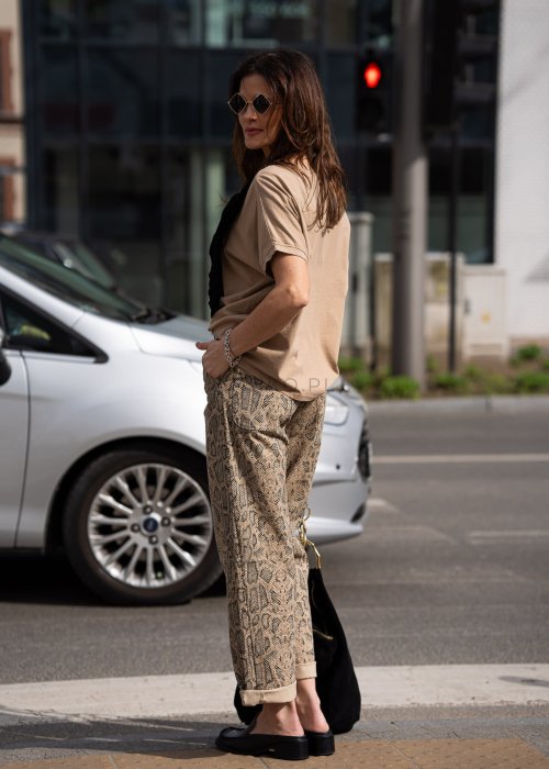 Bluzka damska w odcieniu camel z szerokim dekoltem i krótkim rękawem, zestawiona ze spodniami w zwierzęcy wzór w miejskiej stylizacji.