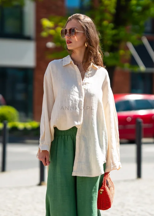 Beżowa lniana koszula damska oversize wykonana z 100% lnu. Model z klasycznym kołnierzykiem, długimi rękawami i wydłużonym tyłem do codziennych oraz eleganckich stylizacji.