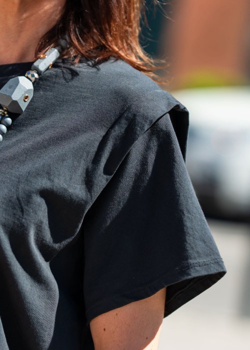 Czarny t-shirt oversize o minimalistycznym fasonie z miękko układającego się materiału. Luźny krój, szerokie rękawy i asymetryczny dół nadają modelowi nowoczesnego charakteru, idealnego do casualowych i miejskich stylizacji.