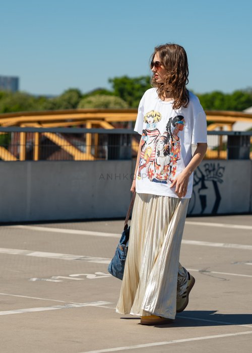 Biała bluzka damska t-shirt z kolorowym nadrukiem postaci i kwiatów, o luźnym kroju, w stylizacji miejskiej z plisowaną spódnicą.
