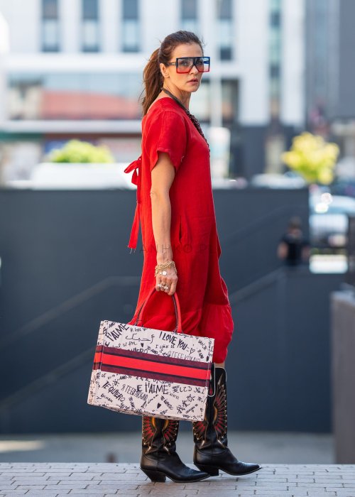 Czerwona lniana sukienka midi z krótkim rękawem i kokardą na plecach, stylizacja z kozakami i dużą torbą w miejskim stylu.