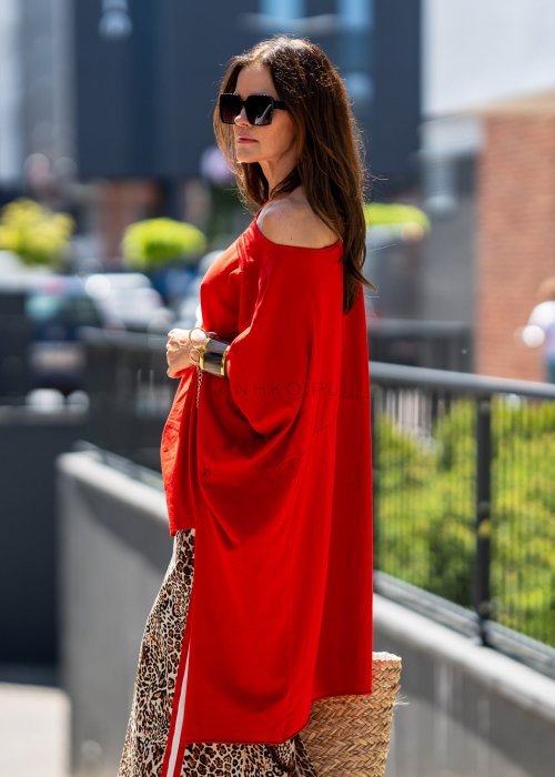 Czerwona bluzka oversize z asymetrycznym dołem i wydłużonym tyłem, zestawiona ze wzorzystą spódnicą. Luźny fason tworzy wyrazistą stylizację.