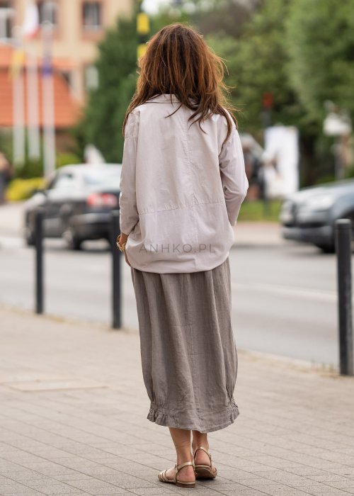 Beżowa koszula oversize z kołnierzem i zapięciem na guziki, o luźnym fasonie i subtelnym przeszyciu z przodu. Stylizacja w neutralnych, naturalnych tonach.