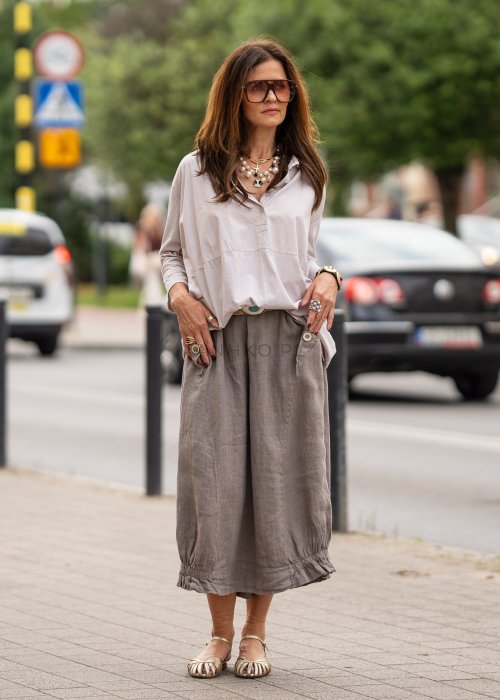 Beżowa koszula oversize z kołnierzem i zapięciem na guziki, o luźnym fasonie i subtelnym przeszyciu z przodu. Stylizacja w neutralnych, naturalnych tonach.