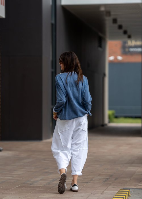 Niebieska bluza oversize w odcieniu denimu z białym ściągaczem przy dekolcie, luźny fason, miejska stylizacja damska.