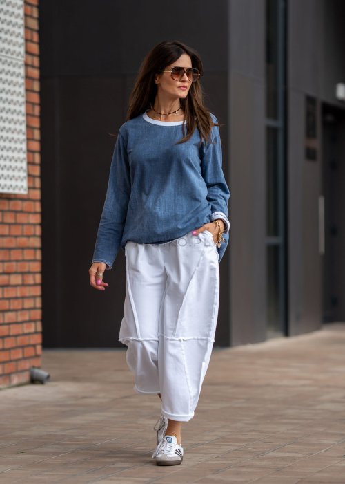 Niebieska bluza oversize w odcieniu denimu z białym ściągaczem przy dekolcie, luźny fason, miejska stylizacja damska.