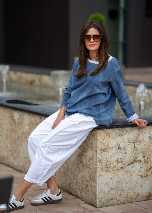 Niebieska bluza oversize w odcieniu denimu z białym ściągaczem przy dekolcie, luźny fason, miejska stylizacja damska.